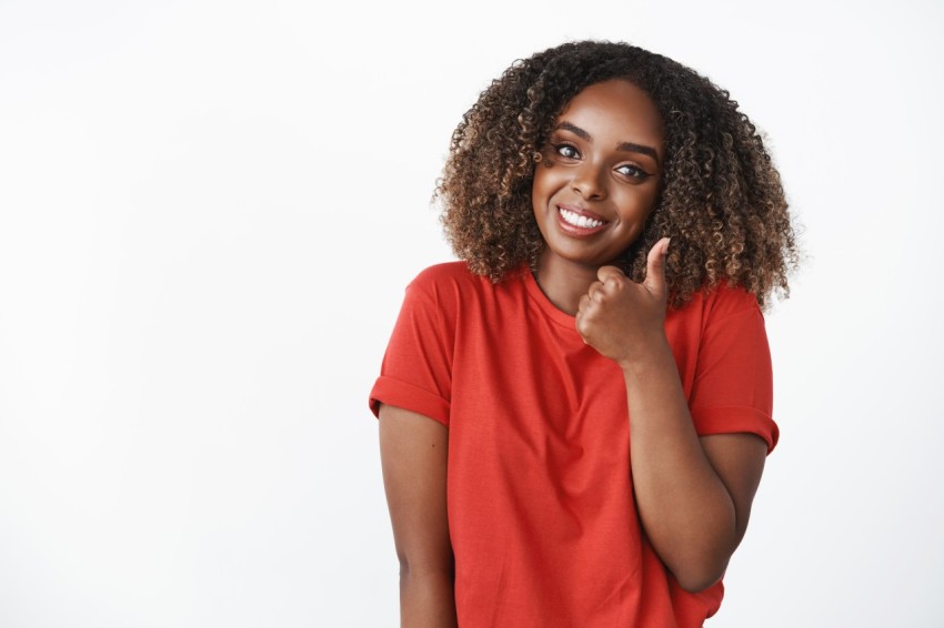 Waist-up shot of cute supportive african american girlfriend showing thumb up in like and approval tilting head and smiling broadly to cheer friend and encourage for excellent efforts over white wall