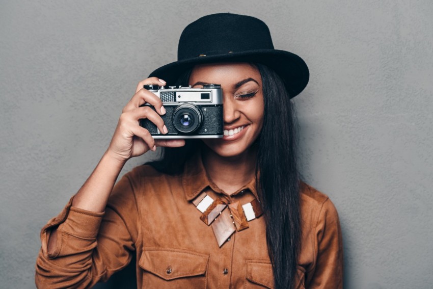 Beautiful cheerful young African woman holding  camera